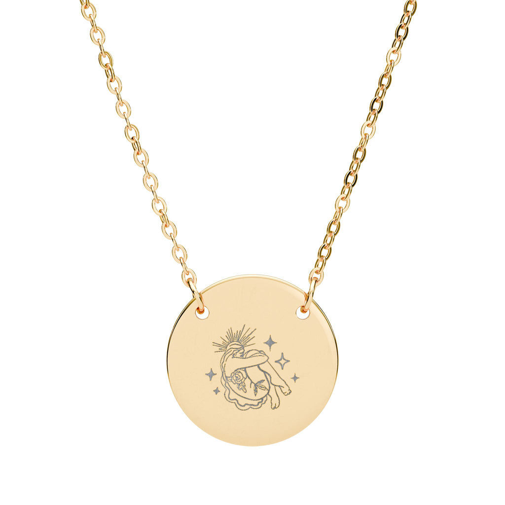 Gold celestial necklace with a round pendant featuring an engraved design on a white background